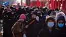 Sepasang suami istri makan sosis bakar saat orang bermasker mengunjungi pameran kuil pada hari kedua perayaan Tahun Baru Imlek di Taman Yuanmingyuan, Beijing, China, Senin (23/1/2023). Tahun Baru Imlek adalah hari libur tahunan terpenting di China. (AP Photo/Andy Wong)