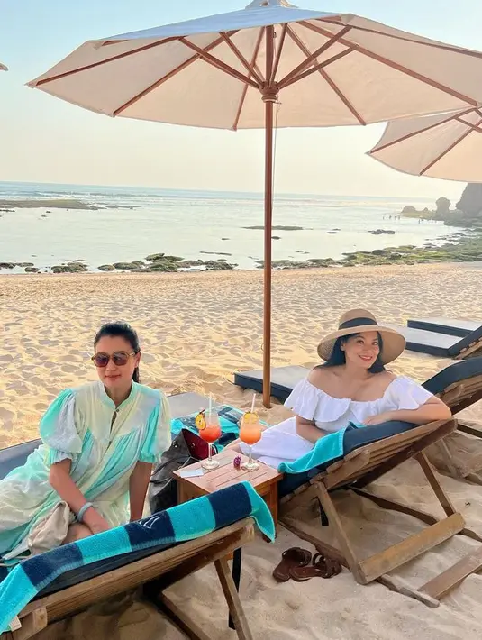 Di Bali, tentu keduanya menikmati pantai. Marcella terlihat mengenakan dress panjang lengan balon warna kebiruan, sementara itu, Titi Kamal mengenakan off shoulder dress putih [@marcella.zalianty/@titi_kamall]