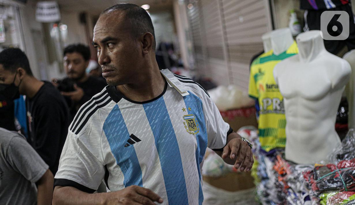 Seorang pria mencoba jersey Argentina tim peserta Piala Dunia 2022 Qatar di salah satu kios di Blok B Pasar Tanah Abang, Jakarta, Jumat (18/11/2022). Jersey sejumlah tim nasional favorit peserta Piala Dunia 2022 Qatar seperti Belanda, Brasil, Jerman, serta Argentina banyak diburu pembeli. (Liputan6.com/Faizal Fanani)