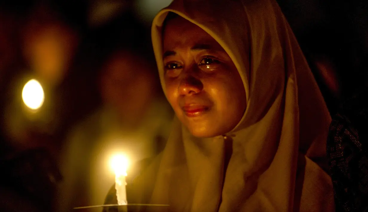 Umat muslim meneteskan air mata ketika mengikuti doa bersama lintas agama saat peringatan setahun tragedi bom gereja Surabaya di luar Gereja Katolik Santa Maria Tak Bercela, Senin (13/5/2019). Pada peringatan itu digelar juga doa lintas agama yang dihadiri sejumlah pemuka agama. (Juni Kriswanto/AFP)