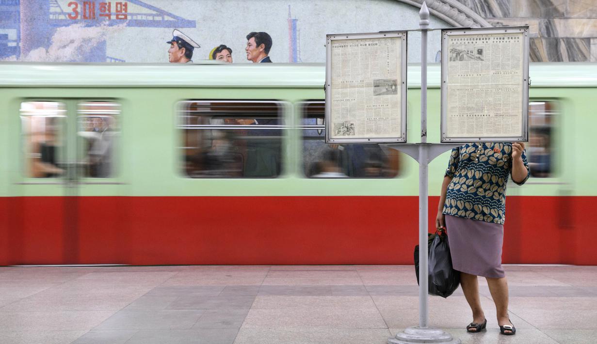 Seorang komuter membaca koran pada platform stasiun kereta bawah tanah atau metro Pyongyang, 6 September 2018. Di stasiun kereta bawah tanah ini tidak terlihatnya iklan laiknya stasiun pada umumnya. (AFP / Ed JONES)