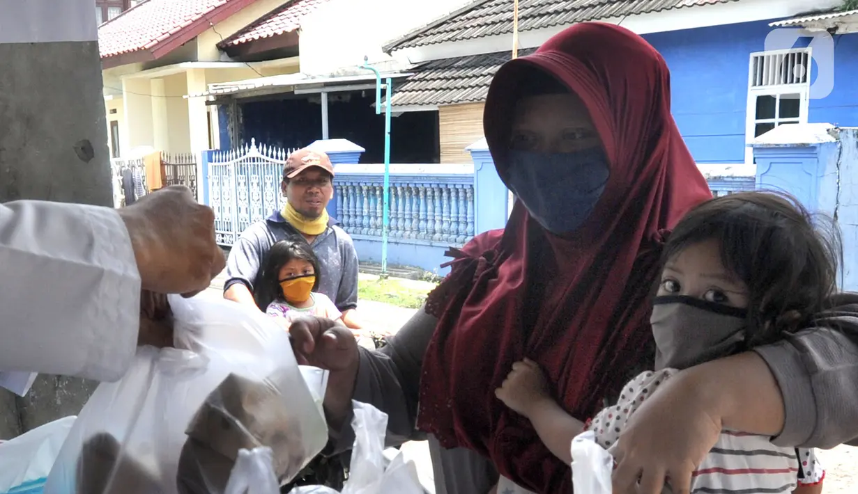 Seorang ibu menggendong menerima nasi bungkus gratis di Kompleks Sinar Pamulang Permai, Pamulang Barat, Tangsel, Senin (13/4/2020). Nasi bungkus gratis ini bentuk kepedulian terhadap mereka yang berpenghasilan rendah dan terdampak perekonomiannya karena penyebaran Covid-19. (merdeka.com/Arie Basuki)