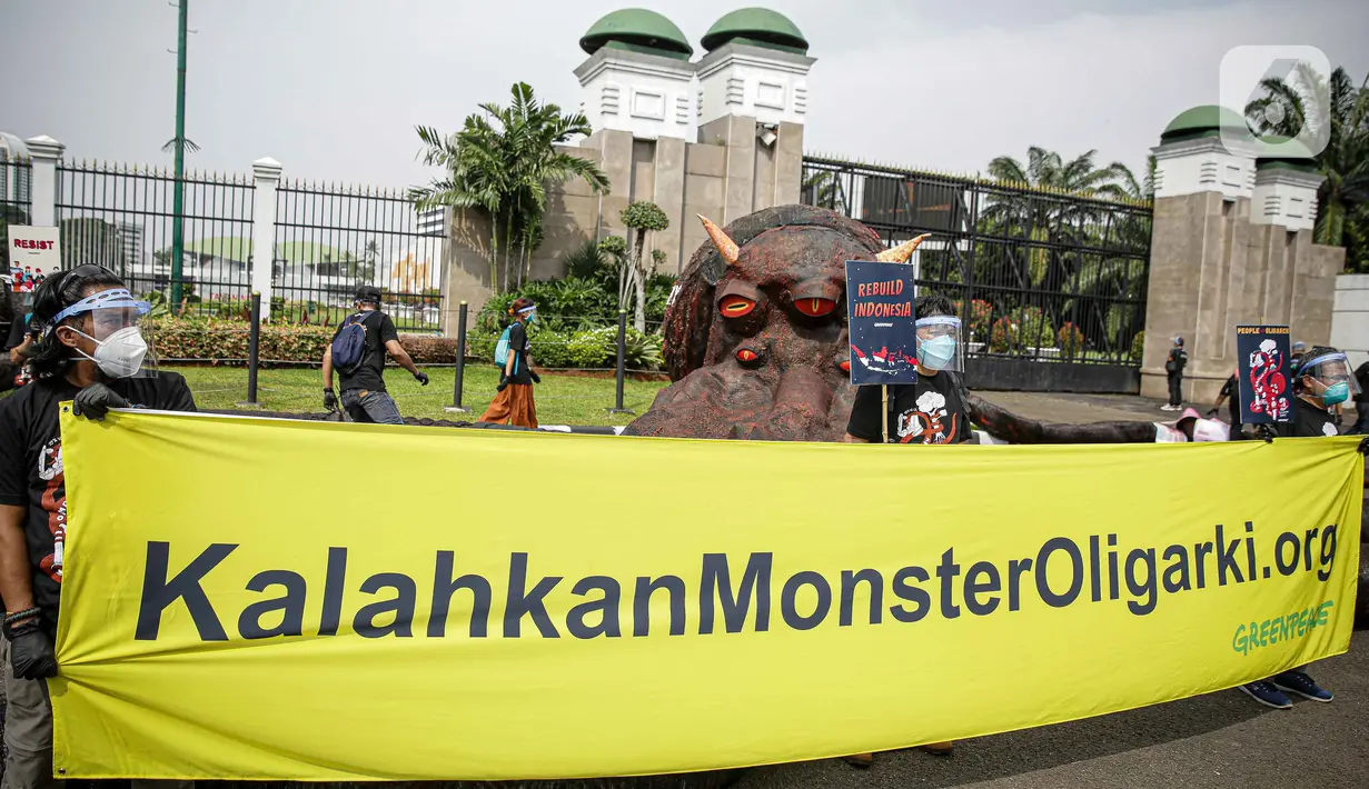 Aktivis Greenpeace membentangkan spanduk saat aksi di depan Gedung DPR RI, Jakarta, Selasa (5/10/2021). Dalam aksinya, mereka membawa gurita raksasa sebagai simbol oligarki serta menyerukan kepada pemerintah agar serius mengatasi pandemi dan memberantas korupsi energi. (Liputan6.com/Faizal Fanani)