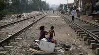 Seorang gadis muda memandikan saudaranya di sebelah jalur kereta api di New Delhi, India, Selasa (16/10). Hasil survei terhadap 104 negara yang dirilis bulan lalu menemukan bahwa sekitar 1,3 miliar orang hidup dalam kemiskinan. (AP Photo/Altaf Qadri)