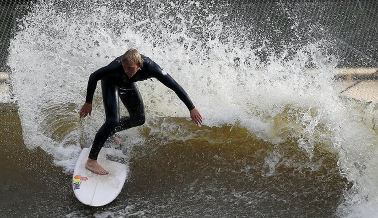 Seorang pria asik berselancar menikmati gelombang buatan yang ada di Surf Snowdonia, Conwy, North Wales, Kamis (3/9/2015).  Danau ini mengabiskan dana hingga ratusan Miliar dan telah dibuka pada tanggal satu Agustus lalu. (REUTERS/Andrew Yates)