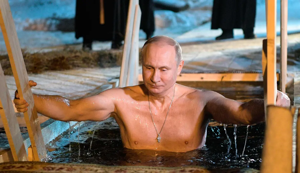 Presiden Rusia Vladimir Putin berendam di air dingin di Danau Seliger di desa Svetlitsa, Rusia (19/1). Ribuan pengikut Gereja Ortodoks Rusia akan berendam ke sungai dan kolam es merayakan Epiphany. (Alexei Druzhinin, Sputnik, Kremlin Pool Photo via AP)