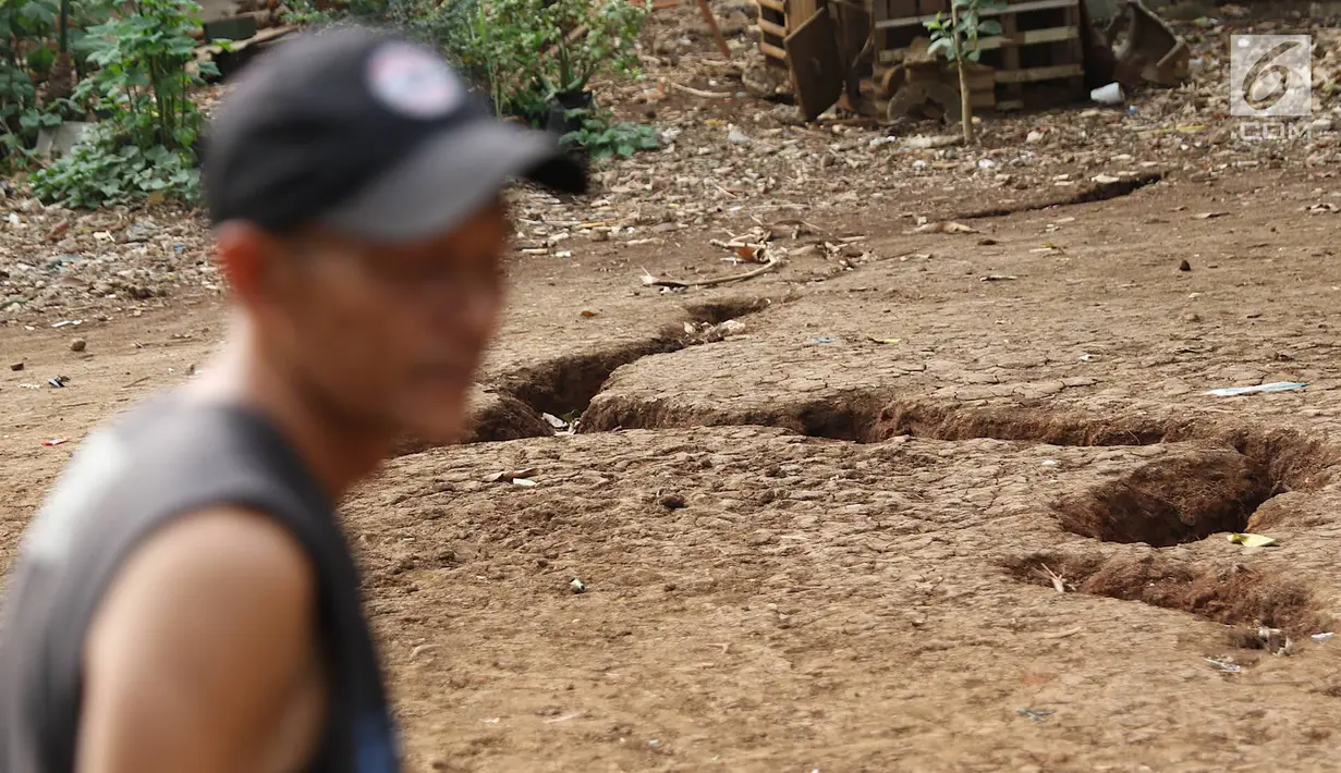 Warga mengamati tanah terbelah di lapangan RT 02 RW 02 Kampung Pedurenan, Kelurahan Cisalak Pasar, Cimanggis, Depok, Jawa Barat, Senin (22/10). Tanah terbelah tersebut terjadi saat hujan deras. (Liputan6.com/Immanuel Antonius)