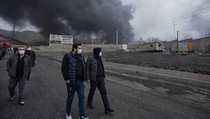 Media lokal Iran melaporkan kebakaran besar terjadi di Teheran dan mengonfirmasi bahwa kilang minyak dan fasilitas penyimpanan minyak terkena dua rudal serangan udara. Tampak dalam foto, empat pria berjalan berlatar kepulan asap tebal dari serangan gabungan AS-Israel terhadap fasilitas penyimpanan minyak pada Sabtu 7 Maret 2026 malam yang membubung ke langit di Teheran, Minggu, 8 Maret 2026. (AP Photo/Vahid Salemi)