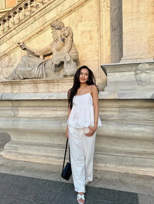 Cantiknya Beby Tsabina saat honeymoon di Italia, pakai outfit serba putih. Ia memadukan tank top bertali spageti dengan celana panjang, serta sandal yang semuanya berwarna putih. [Foto: Instagram/bebytsabina]