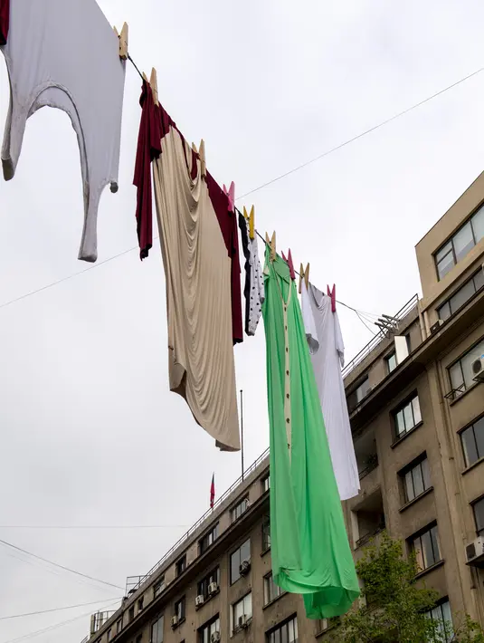 Sejumlah pakaian berukuran besar tergantung di Paseo Bulnes, Santiago (2/10). Pakaian yang dijemur tersebut adalah bagian dari seni instalasi karya seniman Australia "The Glue Society". (AFP Photo/Martin Bernetti)