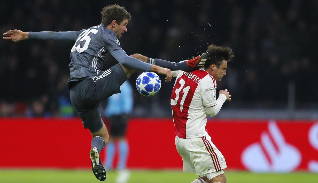 Gelandang Bayern Munchen, Thomas Mueller, menendang kepala bek Ajax Amsterdam, Nicolas Tagliafico, pada laga Liga Champions di Johan Cruyff Arena, Amsterdam, Rabu (12/12). Kedua tim bermain imbang 3-3. (AP/Peter Dejong)