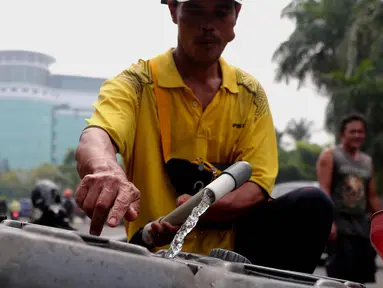 Pedagang tengah mengisi air  bersih ke dalam drigen untuk dijual di Kembangan, Jakarta, Rabu (13/7/2022). Air bersih yang dijual seharga 5 ribu per drigen tersebut untuk memenuhi kebutuhan air bersih bagi warga sekitar kawasan tersebut. (Liputan6.com/Angga Yuniar)
