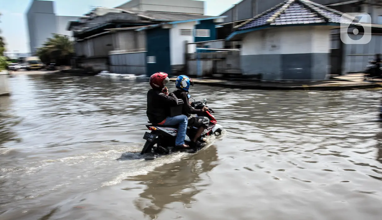 Kendaraan bermotor melintasi jalan yang tergenang air rob (banjir pasang air laut) di Kawasan Pasar Ikan Muara Baru, Jakarta, Kamis (4/6/2020). Banjir rob di Pelabuhan Muara Baru tersebut terjadi akibat cuaca ekstrem serta pasangnya air laut. (Liputan6.com/Faizal Fanani)