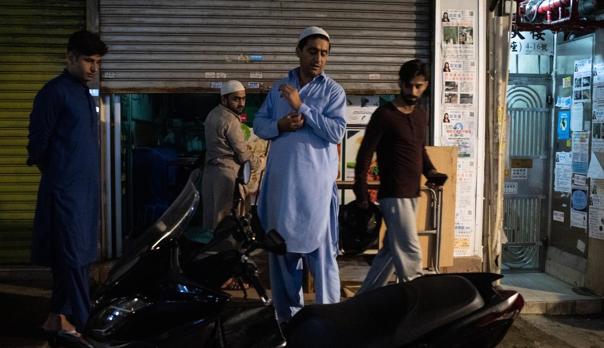 Para imigran Pakistan berkumpul untuk melakukan salat subuh usai menyantap sahur di distrik Kwai Chung, Hong Kong (25/5/2019). Kwai Chung adalah daerah perkotaan di dalam Kota Baru Tsuen Wan di Wilayah Baru Hong Kong. (AFP Photo/Philip Fong)
