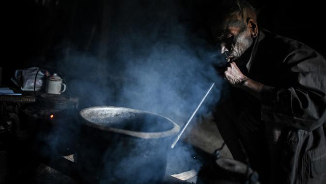 Nok Tan (75), seorang suku Konyak yang bertato memasak dalam rumahnya di sebuah desa di wilayah Sagaing, Myanmar, 9 Februari 2020. Tato bisa menandakan identitas suku, pencapaian kehidupan atau penyelesaian ritual perjalanan. (Ye Aung THU/AFP)