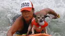 Jill Nakano berselancar dengan anjingnya, Kihei ketika mengikuti kompetisi surfing anjing Petco Unleashed ke-10 di pantai Imperial, California, 1 Agustus 2015. (REUTERS/Mike Blake)