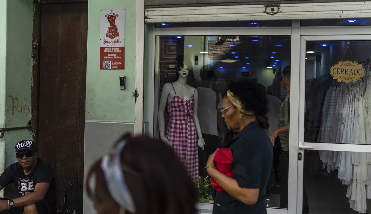 Warga berjalan melewati toko pakaian pribadi yang tutup di Havana, Kuba, Sabtu, 11 November 2023. (AP Photo/Ramon Espinosa)
