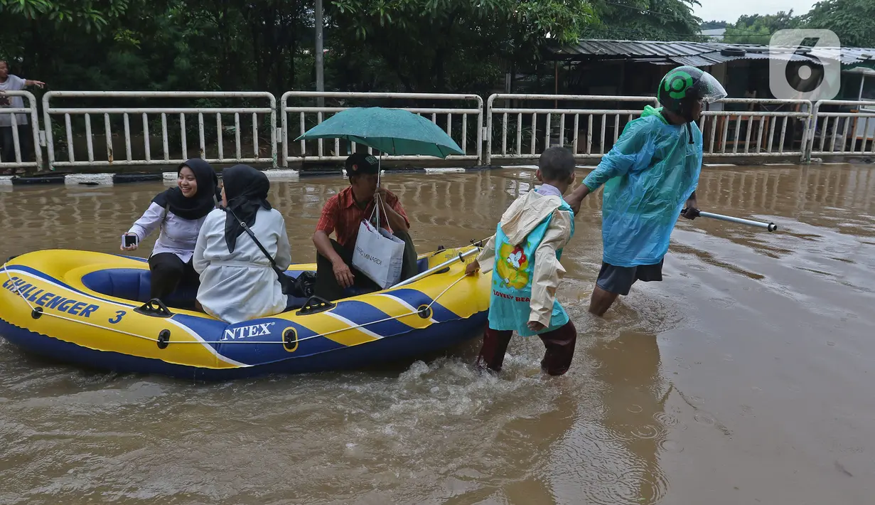Warga menaiki perahu karet saat melintasi kawasan DI Panjaitan, Jakarta, Selasa (25/2/2020). Hujan yang mengguyur Jakarta sejak dini hari tadi membuat kawasan tersebut terendam banjir sehingga tak bisa dilintasi kendaraan bermotor. (Liputan6.com/Herman Zakharia)