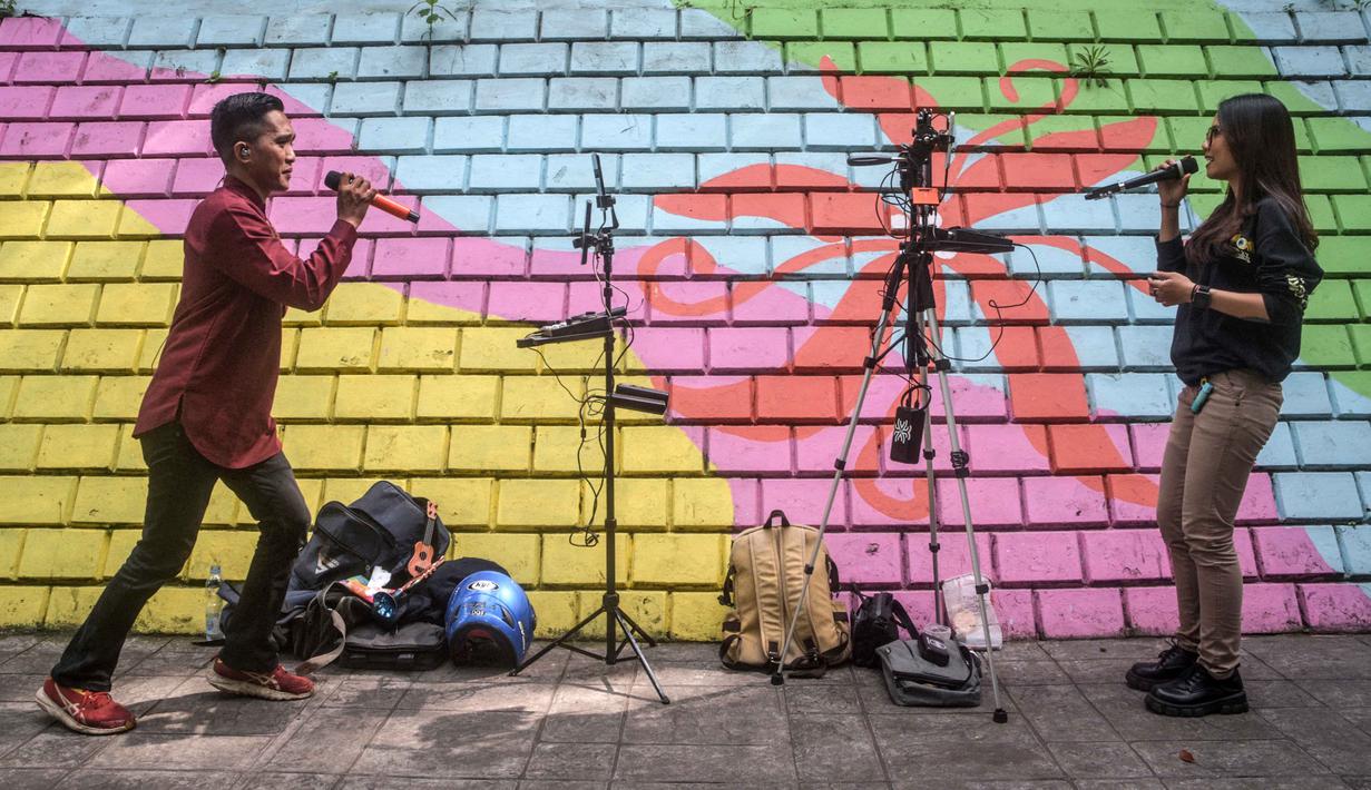 Para penyanyi dalam jaringan (daring/online) menggunakan dinding berwarna-warni sebagai latar belakang tampil untuk menarik penonton agar memberikan donasi digital selama siaran langsung mereka di situs media sosial, Bandung, Jawa Barat, pada Jumat 8 Mei 2026. Fenomena penyanyi yang tampil melalui siaran langsung melalui internet (live streaming) di situs media sosial kian marak. (Timur Matahari/AFP)
