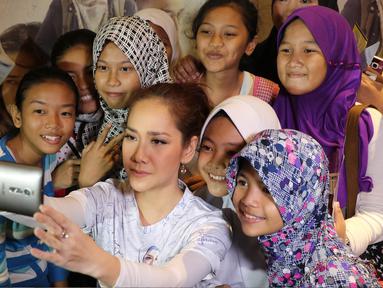 Aktris Bunga Citra Lestari berselfie bersama penggemarnya saat promo film jilbab traveler di kawasan Basuki Rahmat, Jakarta, Selasa (12/07). Pada film yang ditayangkan di bioskop tersebut, BCL harus mengenakan jilbab. (Liputan6.com/Herman Zakharia)
