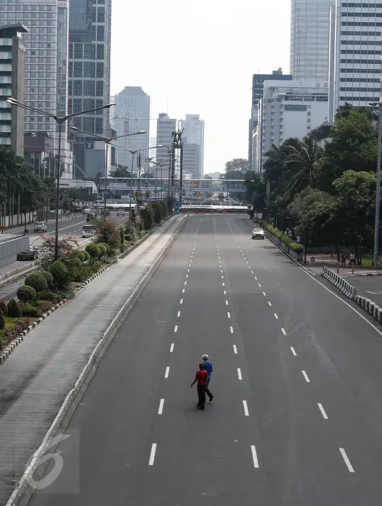 Warga menyeberang melintasi jalan protokol yag lengang di kawasan MH Thamrin, Jakarta, Selasa (6/7). Hampir semua jalan di Ibu Kota lengang saat sebagian besar warga mudik untuk merayakan Lebaran di kampung halaman. (Liputan6.com/Faizal Fanani)