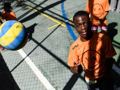Seorang anak mencoba melambungkan bola voli pada program Volleyball Development Training yang digagas oleh FIVB di Formiga favela, Rio de Janeiro, (2/8/2016). (AFP/Leon Neal)