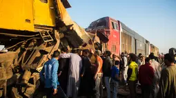 Warga memeriksa kondisi kereta usai tabrakan di dekat Kom Hamadah, Provinsi Beheira, Mesir, Rabu (28/2). Tabrakan terjadi setelah lepasnya dua gerbong kereta penumpang dan ditabrak kereta kargo yang melintas di jalur yang sama. (AFP FOTO/Fayed El-Geziry)