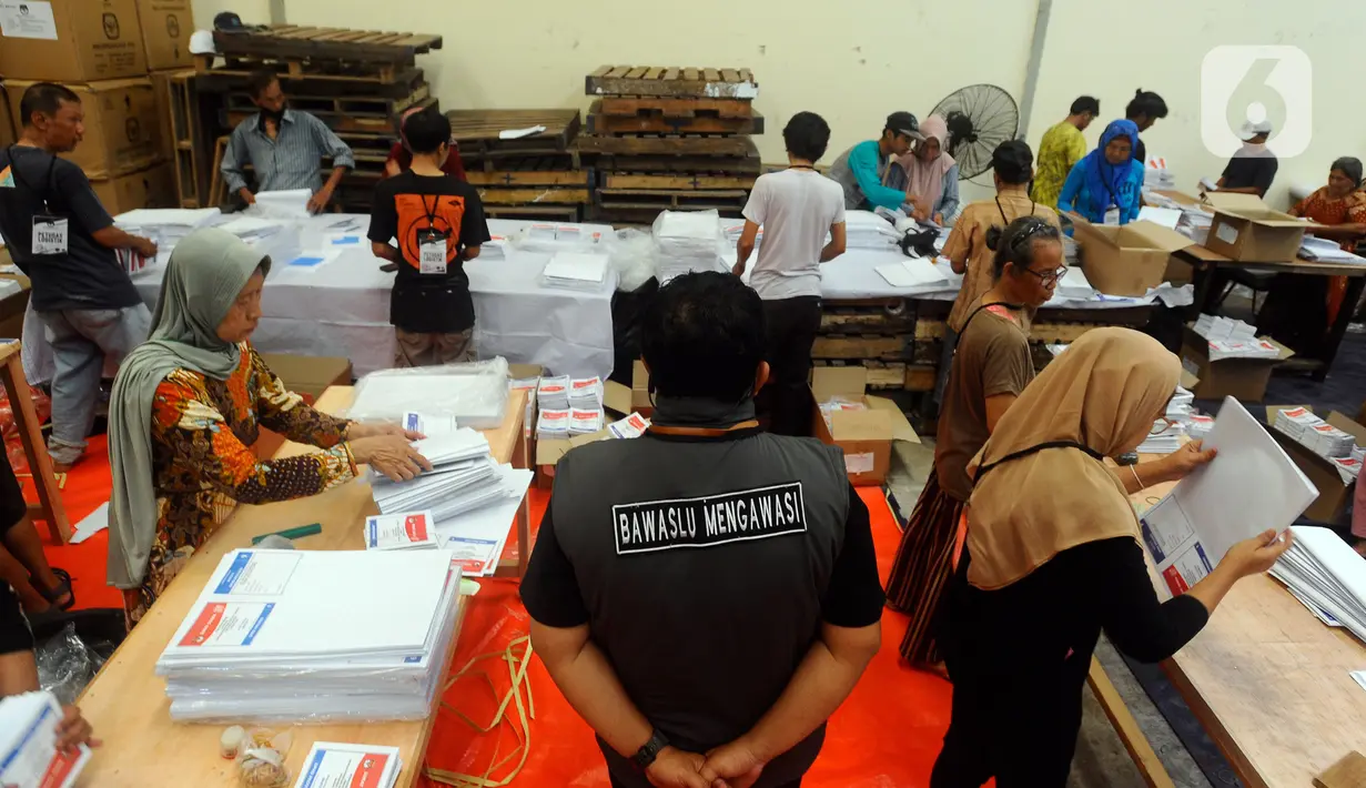 Anggota Bawaslu Tangerang Selatan mengawasi langsung pekerja yang melipat surat suara di gudang logistik. (merdeka.com/Arie Basuki)