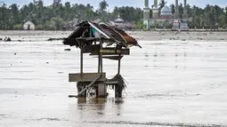 Kerusakan juga terjadi pada jaringan irigasi yang mempersulit pengairan, bahkan setelah lumpur dibersihkan, sementara lumpur tebal menyulitkan pemulihan lahan. Tampak foto lahan pertanian yang berada di samping masjid terendam lumpur setelah banjir bandang di Meureudu, Kabupaten Pidie Jaya, Provinsi Aceh, pada Senin 8 Desember 2025. (Chaideer MAHYUDDIN/AFP)