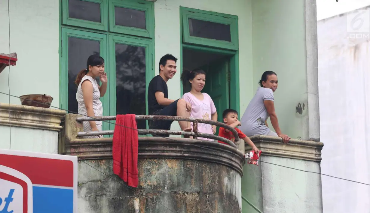 Warga berada di atas teras rumah jelang kirab atau arak-arakan acara resepsi Kahiyang Ayu Siregar-Bobby Nasution di Kota Medan, Sumatera Utara Minggu (26/11). (Liputan6.com/Johan Tallo)