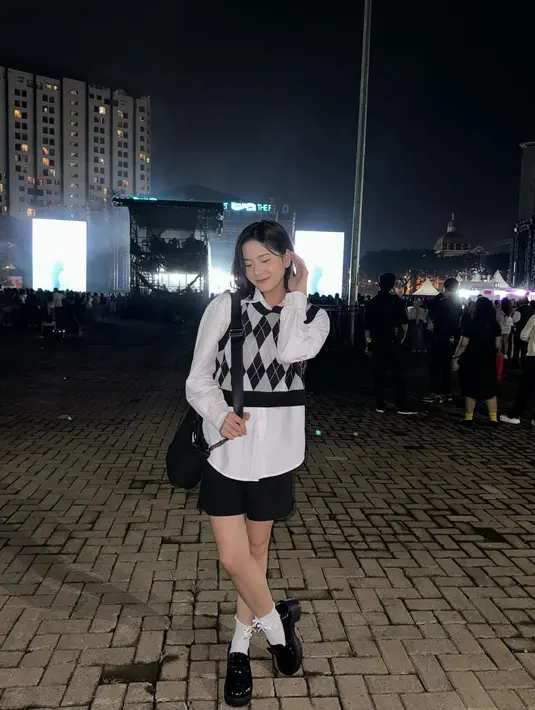 Zee JKT48 tampil chic memadukan antara kemeja putih dengan cropped knitted vest hitam-putih berpola, celana pendek hitam, kaus kaki putih, dan mary jane shoes, serta tas yang sama-sama berwarna hitam. [Foto: Instagram/jkt48.zee]