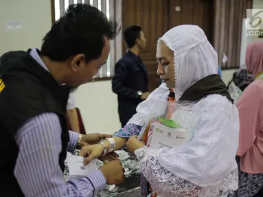 Panitia Penyelenggara Ibadah Haji (PPIH) memberikan gelang untuk calon jemaah haji kloter pertama di Asrama Haji, Jakarta, Sabtu (6/7/2019). Sebelum diberangkatkan, petugas mengecek kembali 385 calon jamaah untuk melakukan kelengkapan administrasi. (Liputan6.com/Faizal Fanani)