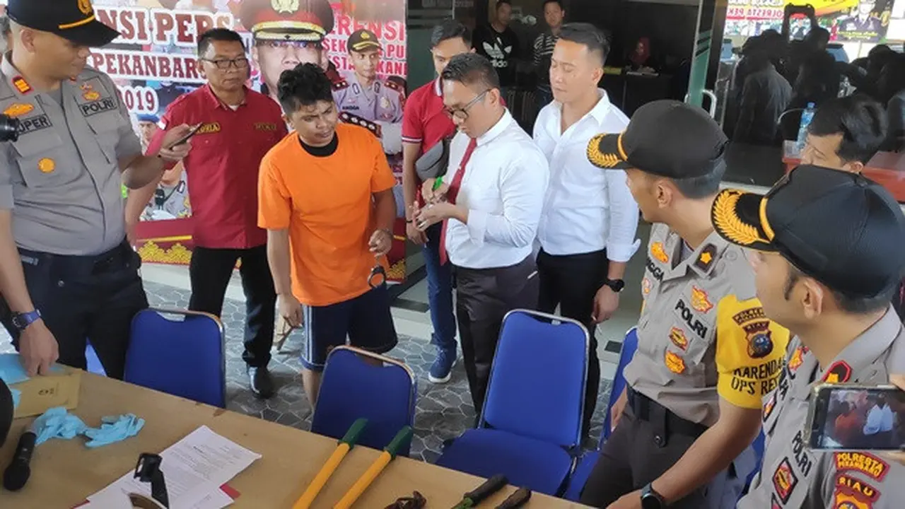 Salah satu tersangka pembobolan minimarket di Pekanbaru menunjukkan ke polisi bagaimana mencongkel gembok.