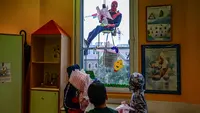 Orang-orang berpakaian seperti “Super Hero” mengantarkan telur Paskah kepada anak-anak yang dirawat di bangsal anak di klinik De Marchi, pada 28 Maret 2024 di Milan, Italia. (Piero Cruciatti/AFP)