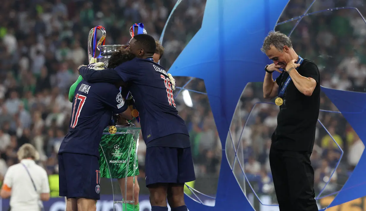 Pelatih PSG, Luis Enrique tengah mengatur posisi medalinya saat di atas podium setelah memastikan timnya menjuarai Liga Champions 2024/2025 dengan mengalahkan Inter Milan dalam laga final yang berlangsung di Allianz Arena, Munchen, Jerman, Minggu (01/06/2025) dini hari WIB. (AFP/Franck Fife)
