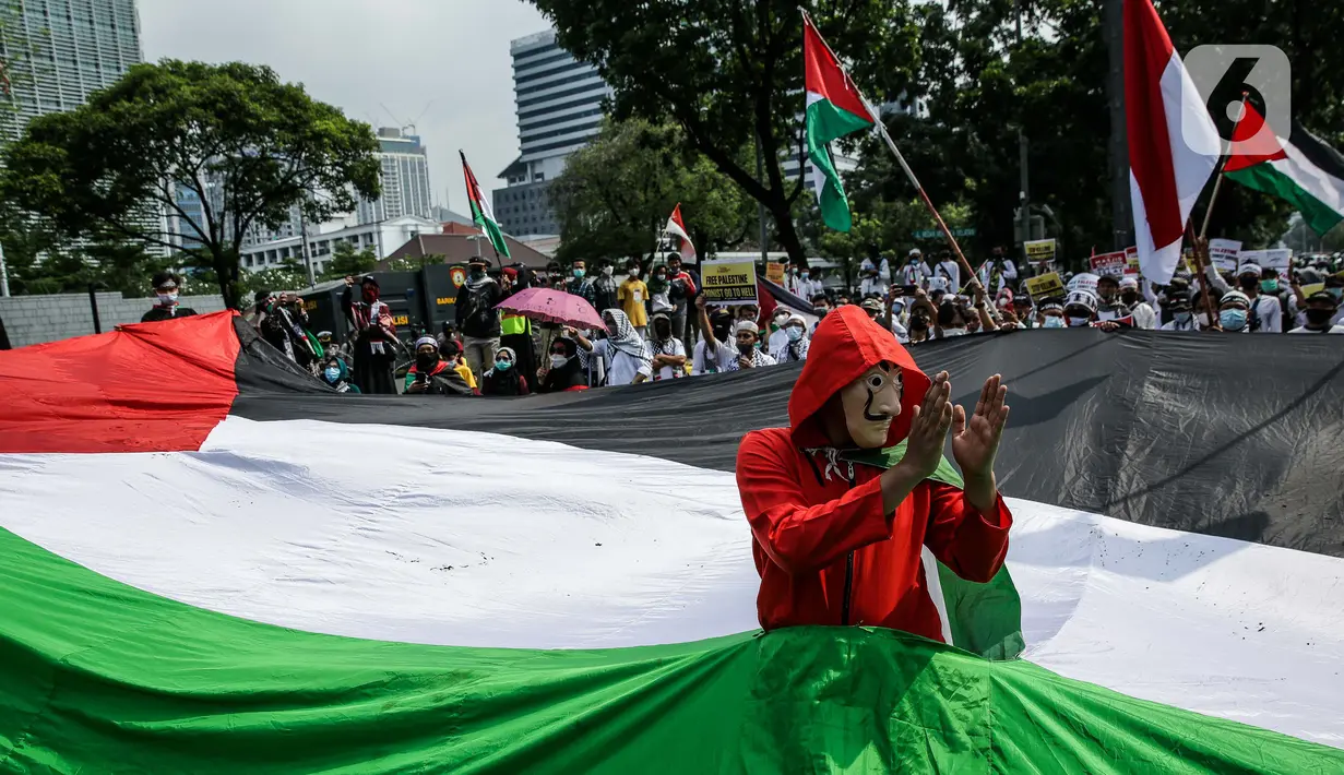 Pengunjuk rasa membentangkan bendera Palestina di depan Kedubes Amerika Serikat, Jumat (21/5/2021). Aksi yang diikuti berbagai elemen masyarakat dan ormas itu mengutuk serangan Israel dan mengajak masyarakat Indonesia untuk mendukung dan membantu Palestina. (Liputan6.com/Faizal Fanani)