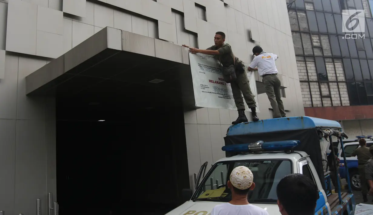 Petugas Satpol PP memasang banner penutup  saat menyegel Diskotek Exotic di Mangga Besar, Jakarta, Kamis (19/4). Dalam proses penyegelan Diskotek Exotic itu tak terlihat aparat kepolisian yang mendampingi Satpol PP. (Liputan6.com/Arya Manggala)