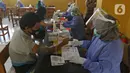 Petugas medis mengecek kesehatan warga sebelum divaksin di MTs As-Syafiiyah, Cilangkap, Jakarta, Kamis (3/6/2021).  Vaksinasi massal bagi warga RT 03/RW 03 Cilangkap, Cipayung, Jakarta Timur menggunakan vaksin produksi AstraZeneca. (Liputan6.com/Herman Zakharia)