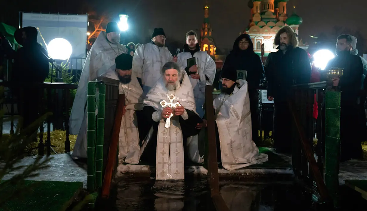 Seorang pendeta Kristen Ortodoks Rusia memberkati air es saat perayaan Epiphany di Gereja Tritunggal Mahakudus, Ostankino, Moskow, Rusia, 18 Januari 2023. Penganut Kristen Ortodoks di Rusia merayakan Hari Raya Epiphany dengan membenamkan diri ke dalam air dingin untuk memperingati pembaptisan Yesus Kristus di Sungai Yordan. (AP Photo/Alexander Zemlianichenko)