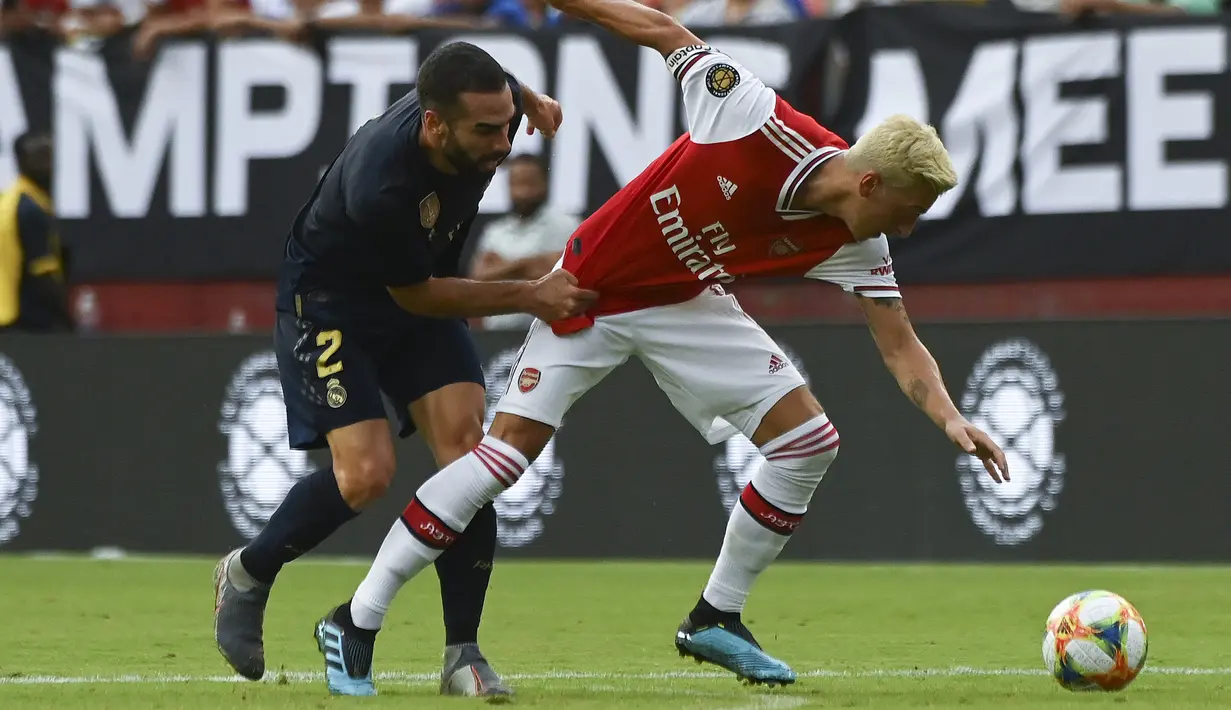 Gelandang Arsenal, Mesut Ozil  membawa bola dari kejaran bek Real Madrid, Dani Carvajal  selama pertandingan International Champions Cup (ICC) 2019 di FedExField, Landover, Maryland (24/7/2019). Madrid menang adu penalti atas Arsenal 3-2 (2-2). (AFP Photo/Andrew Caballero-Reynolds)