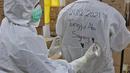 Tenaga kesehatan menulis bagian belakang pakaian APD rekannya di RSDC Wisma Atlet, Jakarta, Selasa (26/1/2021). Data Satgas Covid-19 per Selasa (26/1) mencatat kasus COVID-19 di Indonesia bertambah 13.094 sehingga total menyentuh satu juta, tepatnya 1.012.350. (Liputan6.com/Herman Zakharia)