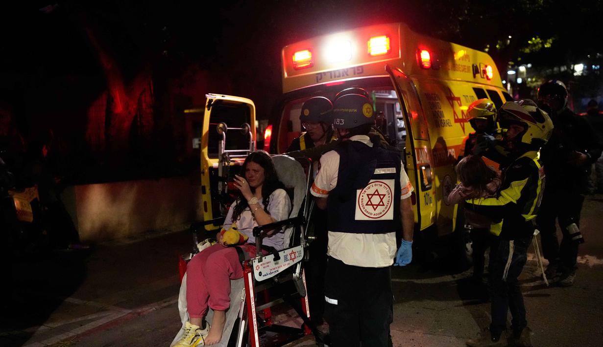 Pesan peringatan dikirimkan melalui ponsel kepada masyarakat Israel untuk mengimbau mereka mencari perlindungan. Tampak dalam foto, seorang petugas penyelamat Israel merawat orang-orang setelah serangan rudal dari Iran di Tel Aviv, Israel, Sabtu 28 Februari 2026. (AP Photo/Ohad Zwigenberg)