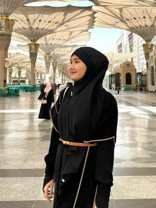 Di tanah suci, Erina yang tengah hamil pun tampil dengan abaya warna hitam senada dengan kerudung panjangnya. Ia pun mengenakan belt coklatnya. [@erinagudono]