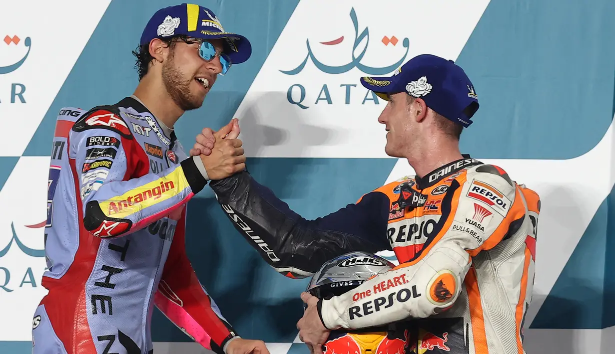 Pembalap tim Gresini Racing Enea Bastianini (kiri) yang menempati tempat pertama mengucapkan selamat kepada pembalap tim Repsol Honda Pol Espargaro di podium setelah balapan perdana MotoGP 2022 seri Qatar GP di Sirkuit Internasional Lusail, Minggu (6/3/2022). (KARIM JAAFAR/AFP)