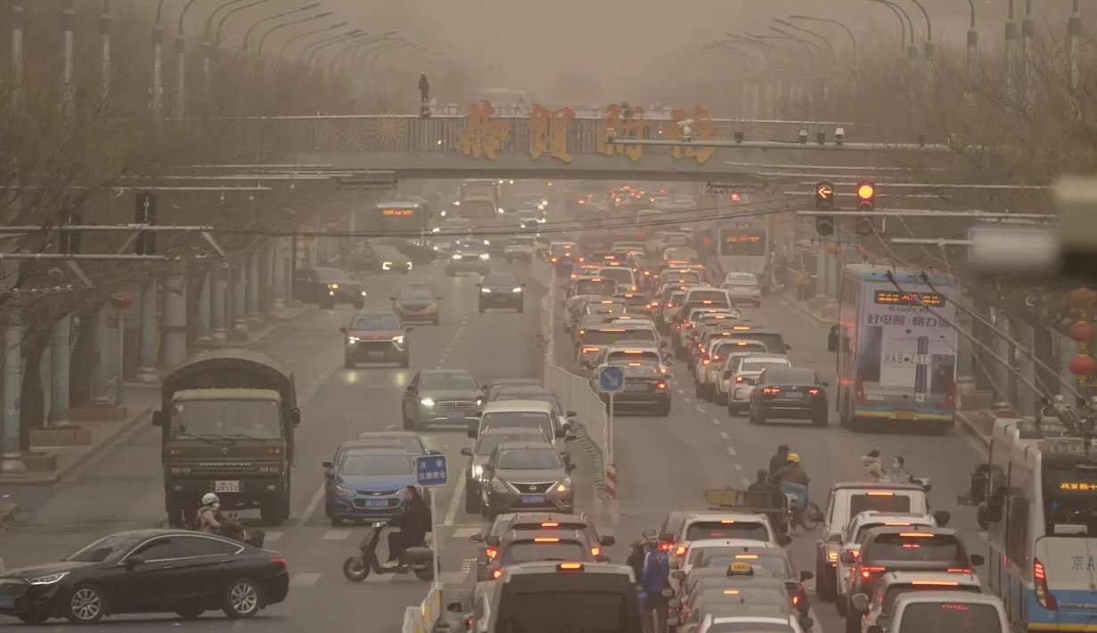 Mobil dan pejalan kaki menyusuri jalan yang diselimuti debu dan kabut di Beijing, Jumat, 10 Maret 2023. Pencakar langit menghilang ke dalam kabut dan kualitas udara anjlok saat ibu kota China diselimuti badai debu dan polusi berat. (AP Photo/Mark Schiefelbein)
