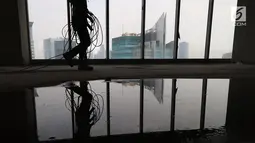 Pekerja Nusa Konstruksi Enjiniring melintas di kaca gedung World Capital Tower, di kawasan Mega Kuningan, Jakarta, Rabu (13/9). Gedung setinggi 54 lantai ini akan menjadi perkantoran kelas atas di ibukota. (Liputan6.com/Fery Pradolo)