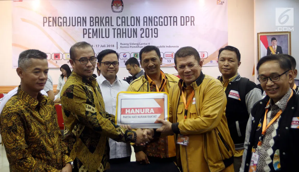 Sekjen Partai Hanura Harry Lontung Siregar (dua kanan) berjabat tangan dengan Komisioner KPU Hasyim Asy'ari (dua kiri) saat menyerahkan berkas pendaftaran bakal calon legislatif di KPU, Jakarta, Selasa (17/7). (Liputan6.com/JohanTallo)