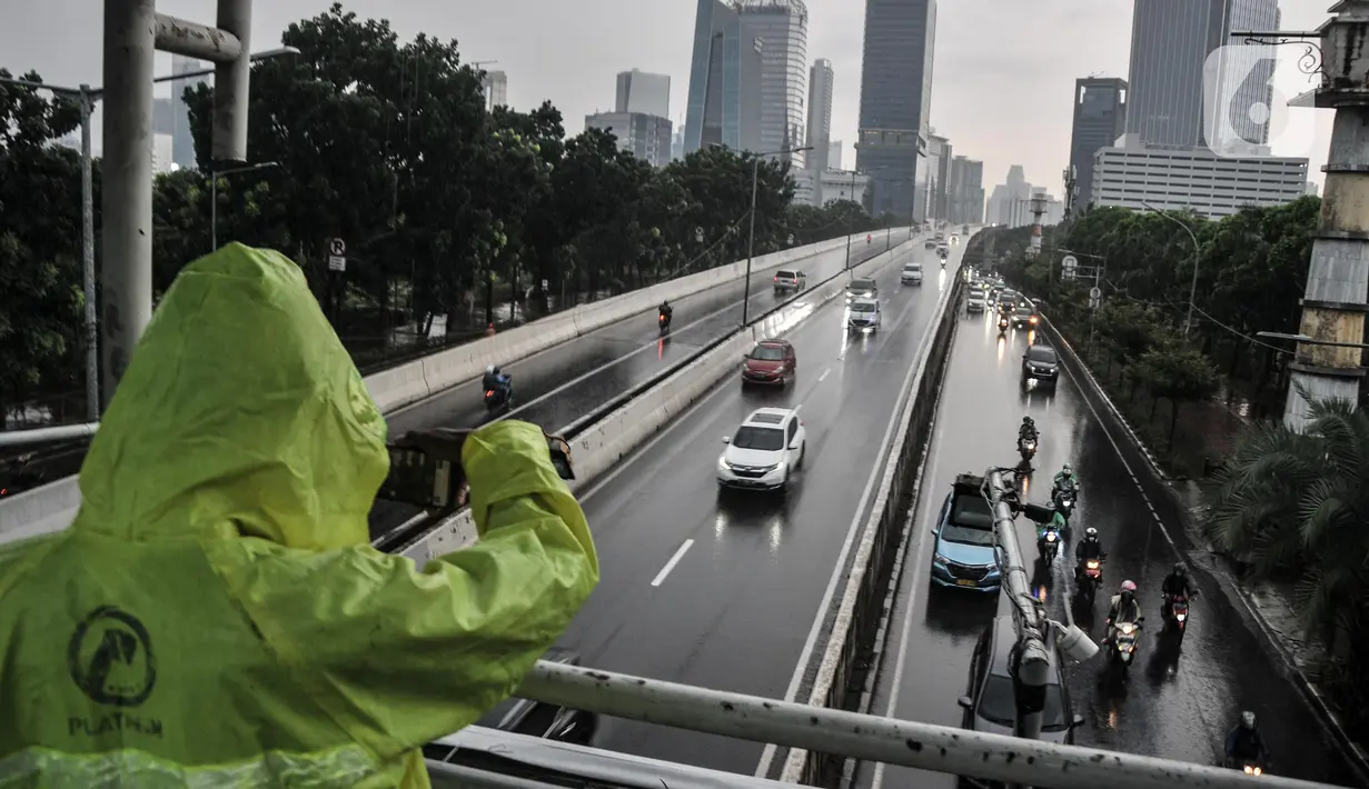 Warga mengenakan jas hujan saat melintasi JPO di Jalan Raya Casablanca, Jakarta Selatan, Selasa (8/3/2022). BMKG memprediksi cuaca ekstrem berupa hujan lebat disertai angin kencang akan terjadi hingga April ini di wilayah Jabodetabek. (merdeka.com/Iqbal S. Nugroho)