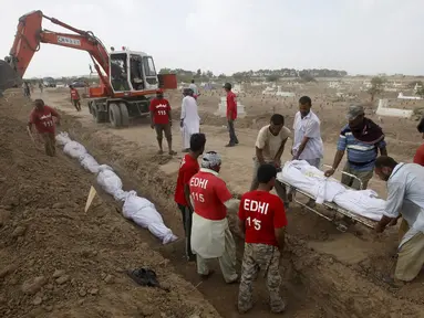 Relawan menguburkan jenazah korban tewas akibat gelombang panas saat pemakaman massal di Karachi, Pakistan, Jumat (26/6/2015). Lebih dari 1.150 orang tewas akibat gelombang panas. (REUTERS/Akhtar Soomro)
