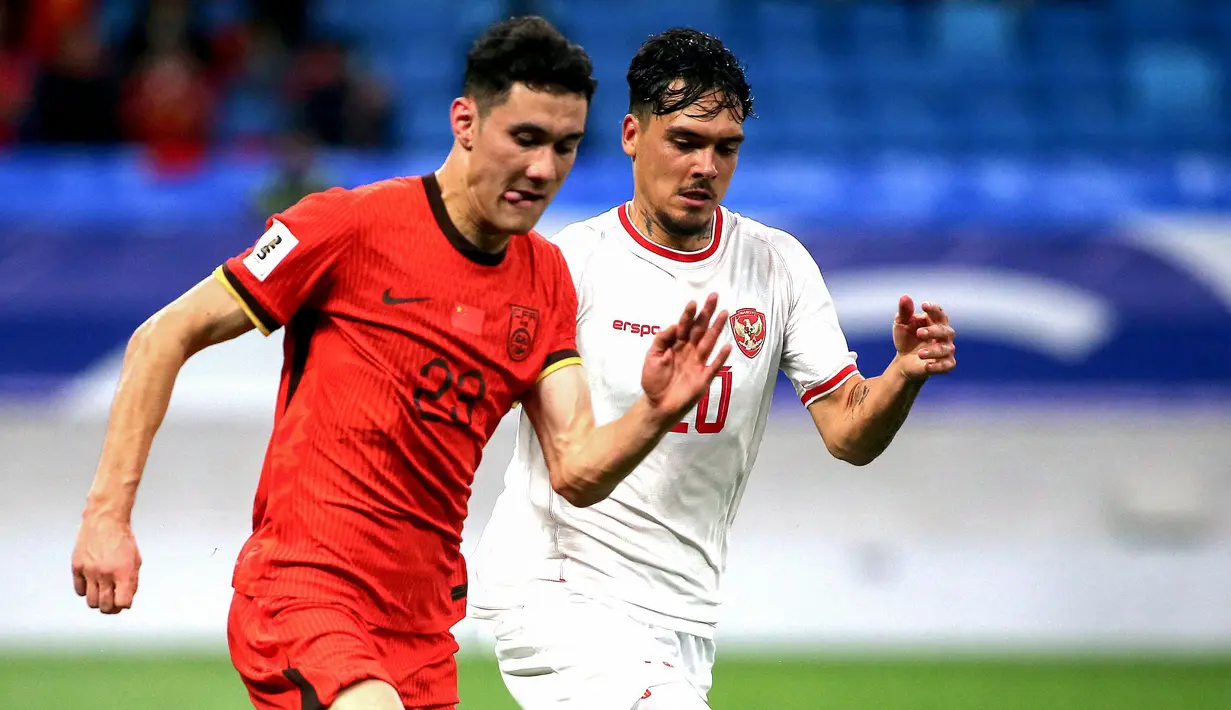 Pemain Timnas Indonesia, Shayne Pattynama (kanan) berebut bola dengan pemain China, Behram Abduweli saat laga lanjutan putaran ketiga Grup C Kualifikasi Piala Dunia 2026 di Qingdao Youth Stadium, Qingdao, China, Selasa (15/10/2024). (AFP)